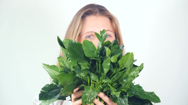 Portrait of a beautiful happy young woman with a bouquet of fresh spinach