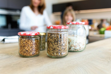 Various uncooked cereals, grains, beans and rice for healthy cooking in glass jars on wooden table...