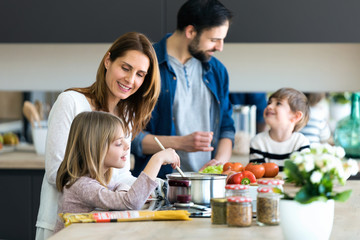 Beautiful cute family having fun while cooking together in the kitchen at home.