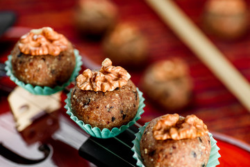 Vegan sweets/ Raw food nutty sweets decorated walnut on a beautiful red violin close-up. Healthy sweets. Desserts without sugar, milk and flour. Series of photos. Close-up. Space