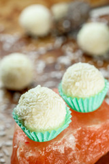 Whites Vegan raw candies with coconut flakes without sugar and milk on a beautiful brass background. raw food dessert. Close-up.