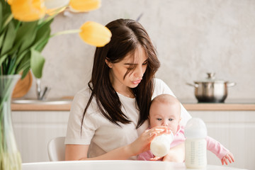 Obraz na płótnie Canvas Young woman siting and feeding baby girl