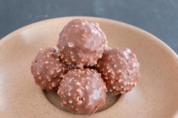 Chocolate & Crushed Almond Crispy Balls on a Light Brown Serving Plate and in Natural Light