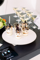 Set of traditional italian desserts tiramisu with chocolate sauce in a glasses. Martini cocktails on the background. Desserts and alcohol on the black table. Birthday party concept