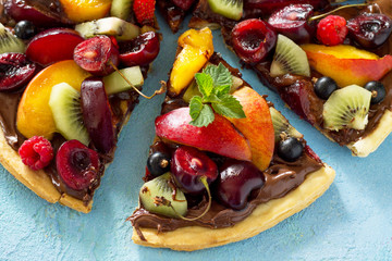 Vitamin dessert. Delicious homemade Summer fruit berry pizza with chocolate paste on a blue stone table.