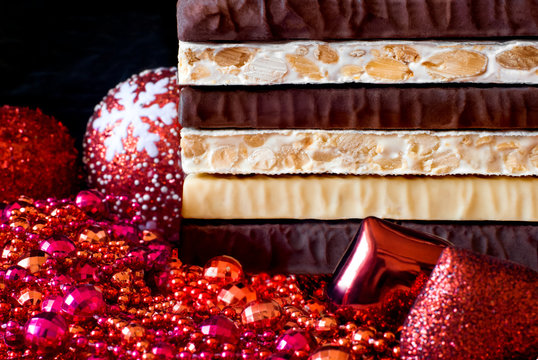 Turron and nougat with nuts. Traditional Spanish Christmas candy. Texture, layers, background. Christmas tree decorations.