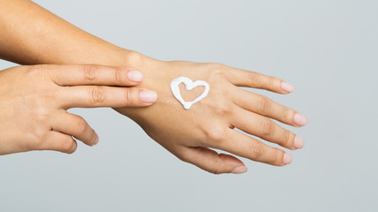 Body care. Cream in heart shape on female hand