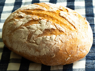 Fresh round bread with a beautiful crust lies on a napkin. Homebaked bread.