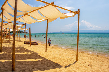 Obraz na płótnie Canvas Ammolofoi Beach, Kavala Region, Northern Greece with tourists and wooden sunshade constructions