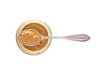 Spoon with nut butter or sesame paste tahini on glass jar. Food ingredient isolated on white background