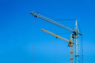 Two cranes against the blue sky.