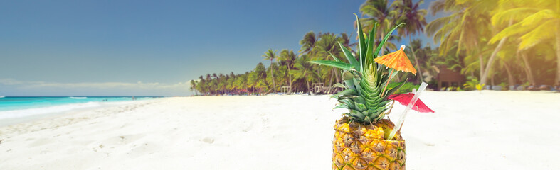 Pineapple cocktail on sand with copy space