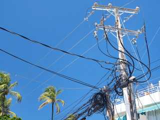 Fototapeta na wymiar Electric tower with untidy cables and wires on blue sky background