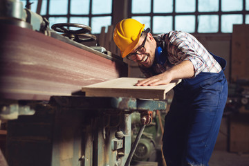 Carpenter working on woodworking machines in carpentry shop