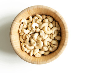 Cashew nuts in wooden plate on white background top view with copy space.