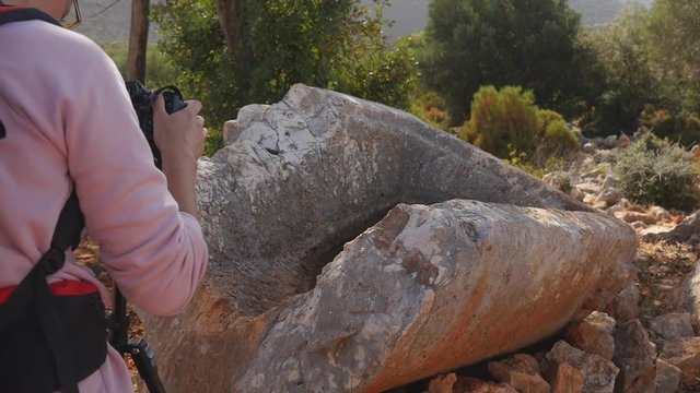 Young woman shooting on camera part of broken crypt in the forest in depths of a forest