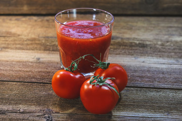 tomatoes and tomato smoothies in a glass on a wooden background.