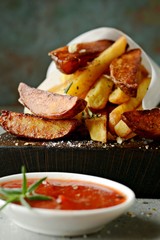 Potato food . Baked potatoes with spices and salt. Tasty french fries on cutting board with ketchup and tomato juice.