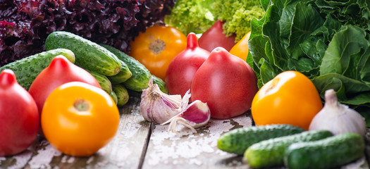 Organic natural vegetables - tomatoes, lettuce, cucumbers and garlic on a wooden background, copy space. Close up