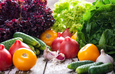 Natural fresh ingredient for cooking vegan salad - tomatoes, cucumber, lettuce on a wooden background. Close up. Copy space.