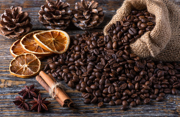 Fresh fragrant coffee beans with cinnamon sticks and dry lemon on a wooden background.