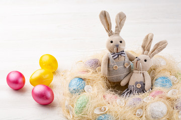 colored eggs and bunnies or hares on white wooden background