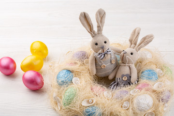 colored eggs and bunnies or hares on white wooden background