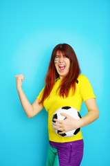 Woman is socccer fan in yellow t-shirt with soccer ball