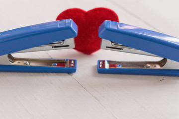 Two staplers and a red heart. Same-sex love concept