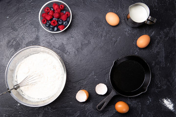 Image of flour, eggs, berries, currants on empty black table