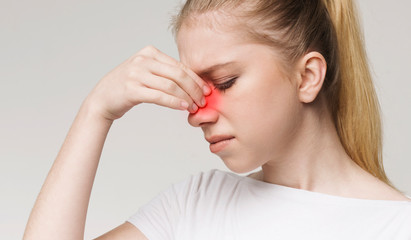 Sad woman holding nose because sinus pain