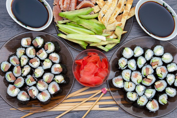 Sushi rolls set served on black stone plate on dark background. Flat lay, top view. Homemade japanese menu.
