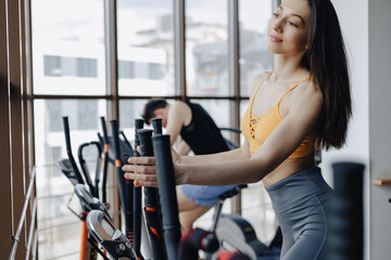 Fototapeta na wymiar young attractive girl at gym on exercise bike, fitness and yoga