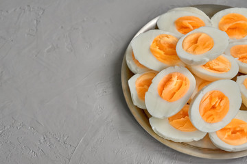 Boiled eggs sliced on wooden cutting board over gray concrete background Top view