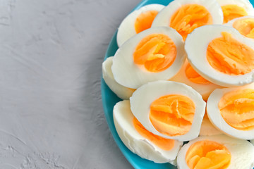 Boiled eggs sliced on wooden cutting board over gray concrete background Top view