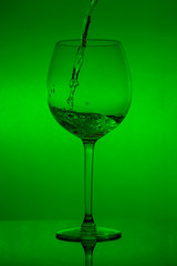 Filling the glass, pouring wineglass on green background