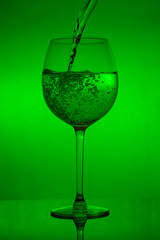 Filling the glass, pouring wineglass on green background
