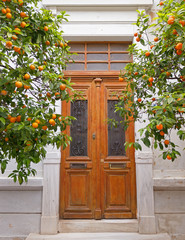 vintage house entrance wooden door and orange trees, Athens Greece