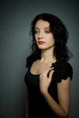 Naklejka premium Amazing young girl with red sensual lips and dark hair posing on black background in studio