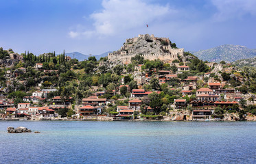a historic fortress with a protective wall at the end of a hill with a long flagpole and flag;...