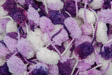 Hanks of white, violet and purple pompons. Knitter background. Top view.