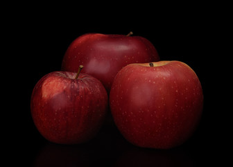 Group of fresh red apples isolated on black background. Different sized apples.
