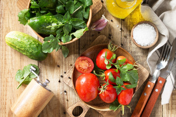 Healthy food: fresh vegetables on the kitchen wooden table. Fresh tomatoes, cucumbers and rucola for cooking salad. Diet menu. Top view flat lay background.