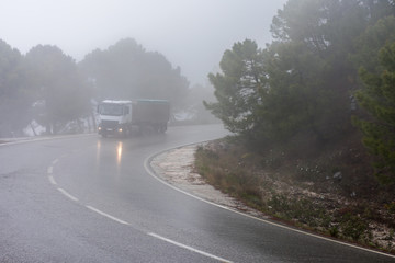 Obraz na płótnie Canvas Camion circulando por un puerto de montaña con niebla