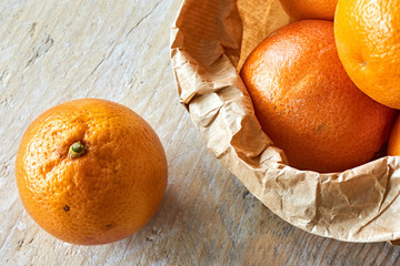 Orange organic blood oranges in brown paper bag on weathered wooden table with copy space flat lay