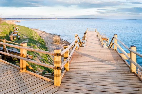 Pedestrian wooden bridge in the park. Place to rest near the lake. View of the park at sunset.