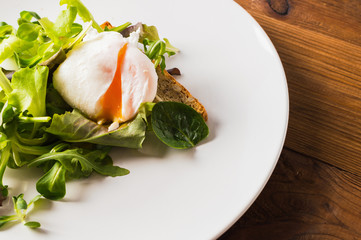 Delicious breakfast. Poached egg with salad and toast.
