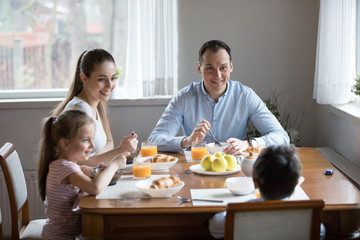 Happy family with children eating morning breakfast at kitchen