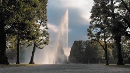 Hannover, Germany. A huge, high jet of water fountain pouring out of a bowl placed on the ground. Against the background of green trees in the park. The concept of sexual relations, sperm, ejaculation