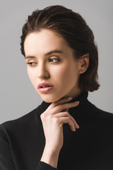 pensive young woman in black jumper isolated on grey